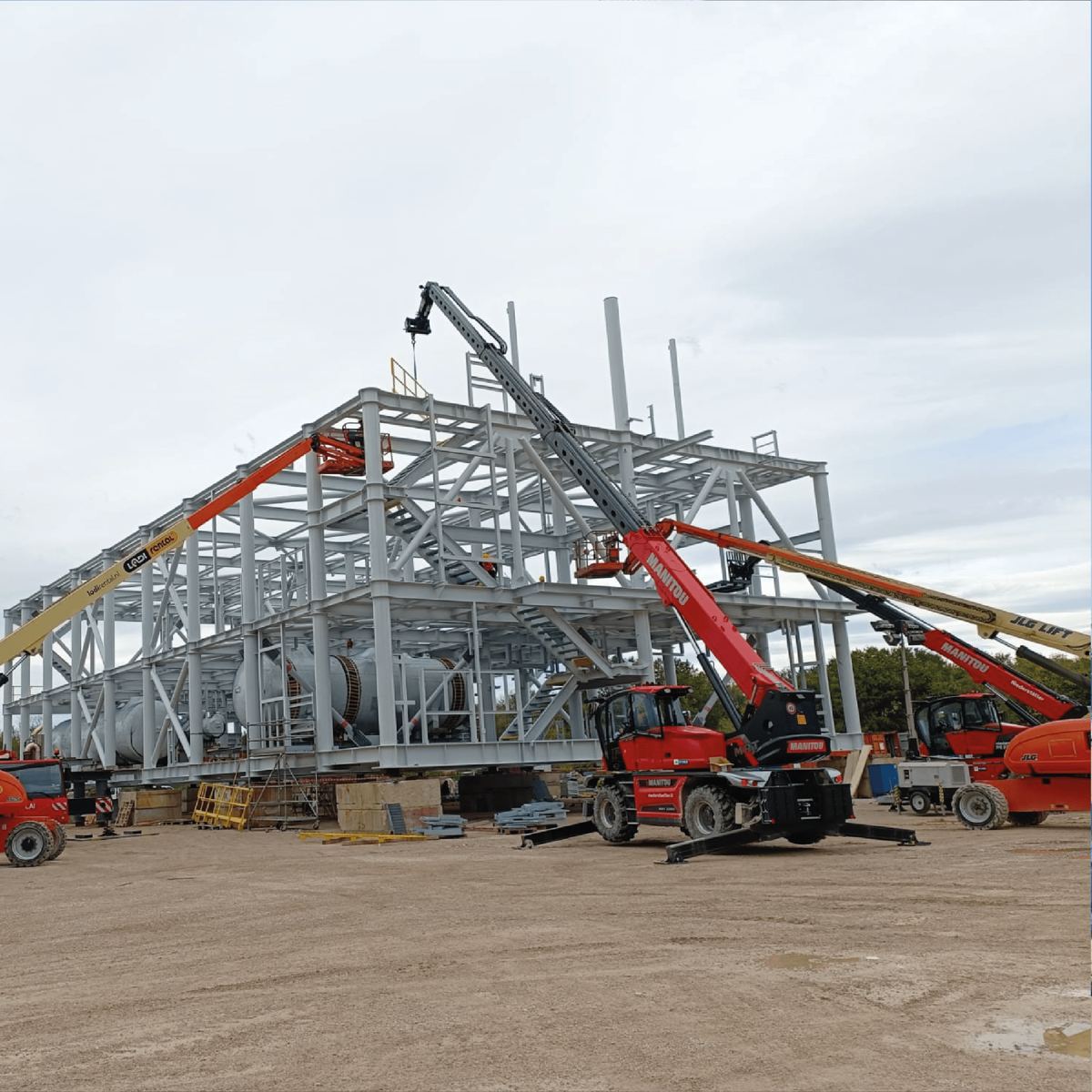 Montaggio di una struttura in acciaio con autogru e piattaforme aeree in cantiere